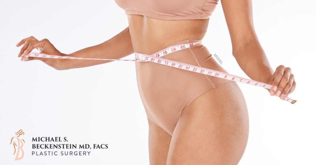 Woman in nude colored undergarments with a tape measure around her waist. (MODEL)